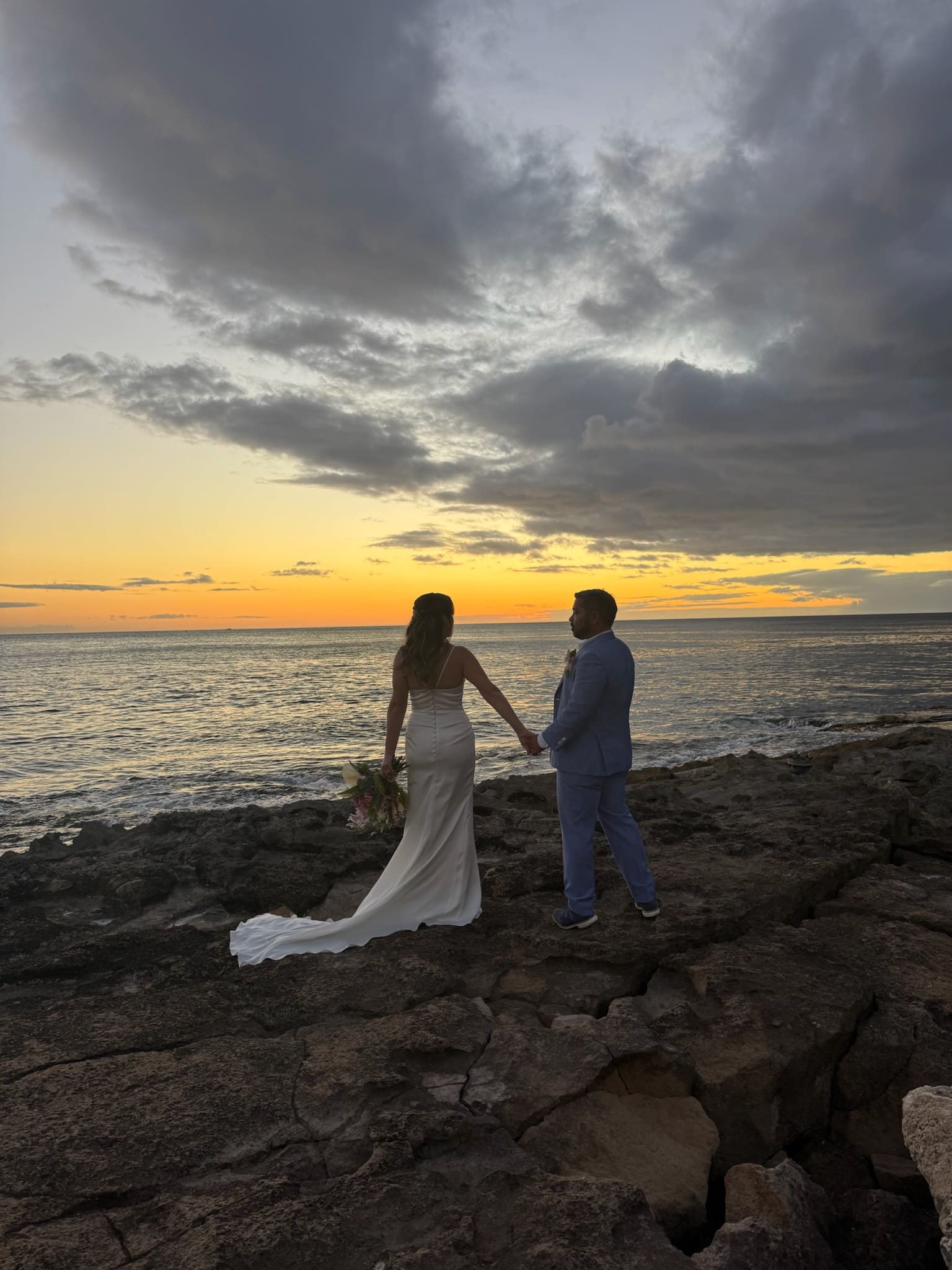 Becca and Jake holding hands on the lava rocks at sunset